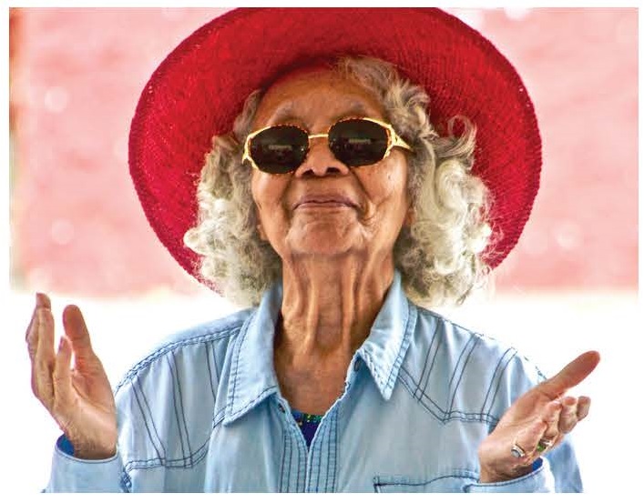Older female adult in sunglasses and red hat